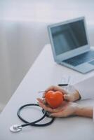 Doctor explaining heart to elderly patient. Doctor explaining the heart model. Doctors pen point to a model of the heart photo