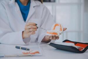 los dentistas están discutiendo problemas dentales al informar la imagen de rayos X en la pantalla del portátil a los pacientes. foto