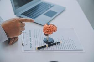 Doctor explaining brain functions to patient on model in office. photo