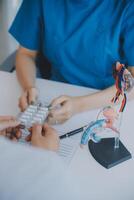 Doctor uses anatomical model to explain male urinary system. Model labeled with parts, doctor points and explains how they work together for urinary function, ensuring patient comprehension. photo