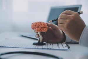 Doctor explaining brain functions to patient on model in office. photo