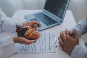 Doctor explaining heart to elderly patient. Doctor explaining the heart model. Doctors pen point to a model of the heart photo