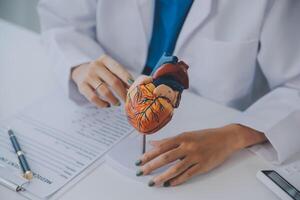 Doctor explaining heart to elderly patient. Doctor explaining the heart model. Doctors pen point to a model of the heart photo