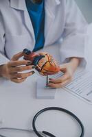 Doctor explaining heart to elderly patient. Doctor explaining the heart model. Doctors pen point to a model of the heart photo