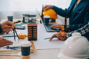 imagen de ingeniero reunión para arquitectónico proyecto. trabajando con compañero y Ingenieria herramientas en lugar de trabajo Clásico tono. foto