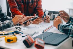 engineer people meeting working and pointing at a drawings in office for discussing. Engineering tools and construction concept. photo