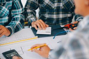 engineer people meeting working and pointing at a drawings in office for discussing. Engineering tools and construction concept. photo