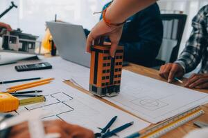 imagen de ingeniero reunión para arquitectónico proyecto. trabajando con compañero y Ingenieria herramientas en lugar de trabajo Clásico tono. foto