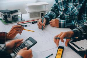 engineer people meeting working and pointing at a drawings in office for discussing. Engineering tools and construction concept. photo