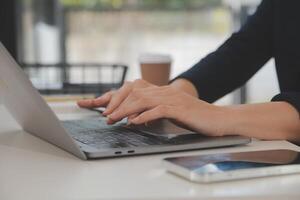 mujer de negocios asiática que usa una computadora portátil y trabaja en la oficina con un documento de calculadora en el escritorio, planificando el análisis del informe financiero, la inversión del plan de negocios, el concepto de análisis financiero. foto