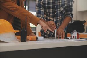 masculino y hembra industrial ingenieros en difícil sombreros discutir nuevo proyecto mientras utilizando ordenador portátil. ellos hacer demostración gestos ellos trabajo en un pesado industria fabricación fábrica. foto