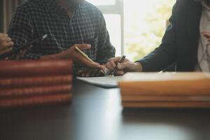 Justice and Law concept. Legal counsel presents to the client a signed contract with gavel and legal law or legal having team meeting at law firm in background photo