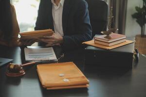 Justice and Law concept. Legal counsel presents to the client a signed contract with gavel and legal law or legal having team meeting at law firm in background photo