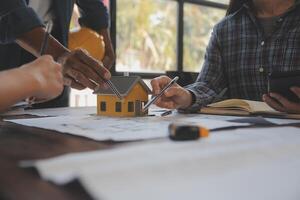 un equipo de construcción ingenieros negociaciones a gerentes y construcción trabajadores a el construcción sitio. calidad inspección, trabajo plan, hogar y industrial edificio diseño proyecto foto