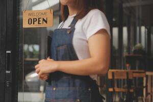 Startup successful small business owner sme beauty girl stand with tablet smartphone in coffee shop restaurant. Portrait of asian tan woman barista cafe owner. SME entrepreneur seller business concept photo