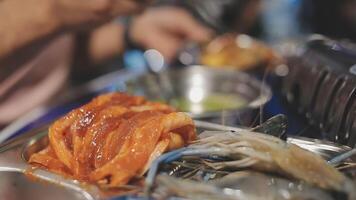 Close up shot of hand cooking Korean grilled pork belly meat and use scissors to cut meat on iron grill pan.pork belly on a grill,samgyupsal,Cooking pork belly on a pan,korean pork barbecue video