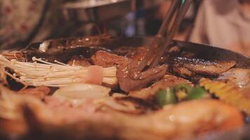 Close up shot of hand cooking Korean grilled pork belly meat and use scissors to cut meat on iron grill pan.pork belly on a grill,samgyupsal,Cooking pork belly on a pan,korean pork barbecue video