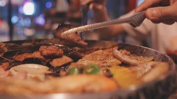 Close up shot of hand cooking Korean grilled pork belly meat and use scissors to cut meat on iron grill pan.pork belly on a grill,samgyupsal,Cooking pork belly on a pan,korean pork barbecue video