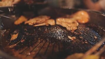 vicino su tiro di mano cucinando coreano grigliato Maiale pancia carne e uso forbici per tagliare carne su ferro griglia padella.maiale pancia su un' griglia, samgyupsal, cucina Maiale pancia su un' padella, coreano Maiale barbecue video