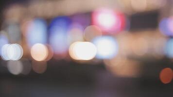 Beautiful bokeh in a dark blurry background at night on the walking street with the people. The round colorful bokeh shine from buildings and shops in the city lifestyle. Abstract concept. video