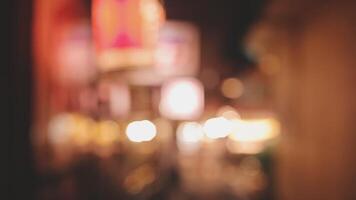 Beautiful bokeh in a dark blurry background at night on the walking street with the people. The round colorful bokeh shine from buildings and shops in the city lifestyle. Abstract concept. video