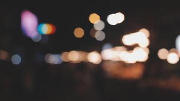 schön Bokeh im ein dunkel verschwommen Hintergrund beim Nacht auf das Gehen Straße mit das Personen. das runden bunt Bokeh scheinen von Gebäude und Geschäfte im das Stadt Lebensstil. abstrakt Konzept. video