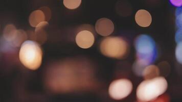 Beautiful bokeh in a dark blurry background at night on the walking street with the people. The round colorful bokeh shine from buildings and shops in the city lifestyle. Abstract concept. video