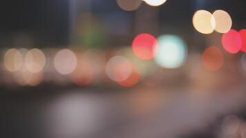 schön Bokeh im ein dunkel verschwommen Hintergrund beim Nacht auf das Gehen Straße mit das Personen. das runden bunt Bokeh scheinen von Gebäude und Geschäfte im das Stadt Lebensstil. abstrakt Konzept. video