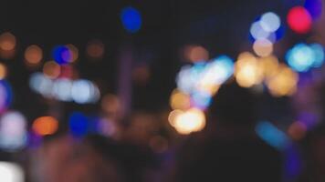 Beautiful bokeh in a dark blurry background at night on the walking street with the people. The round colorful bokeh shine from buildings and shops in the city lifestyle. Abstract concept. video