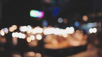 Beautiful bokeh in a dark blurry background at night on the walking street with the people. The round colorful bokeh shine from buildings and shops in the city lifestyle. Abstract concept. video