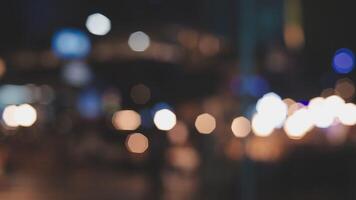 Beautiful bokeh in a dark blurry background at night on the walking street with the people. The round colorful bokeh shine from buildings and shops in the city lifestyle. Abstract concept. video