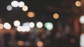 Beautiful bokeh in a dark blurry background at night on the walking street with the people. The round colorful bokeh shine from buildings and shops in the city lifestyle. Abstract concept. video