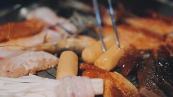 Close up shot of hand cooking Korean grilled pork belly meat and use scissors to cut meat on iron grill pan.pork belly on a grill,samgyupsal,Cooking pork belly on a pan,korean pork barbecue video