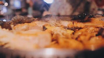 vicino su tiro di mano cucinando coreano grigliato Maiale pancia carne e uso forbici per tagliare carne su ferro griglia padella.maiale pancia su un' griglia, samgyupsal, cucina Maiale pancia su un' padella, coreano Maiale barbecue video