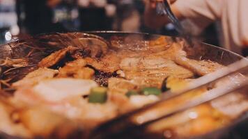 Close up shot of hand cooking Korean grilled pork belly meat and use scissors to cut meat on iron grill pan.pork belly on a grill,samgyupsal,Cooking pork belly on a pan,korean pork barbecue video