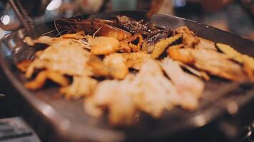 Close up shot of hand cooking Korean grilled pork belly meat and use scissors to cut meat on iron grill pan.pork belly on a grill,samgyupsal,Cooking pork belly on a pan,korean pork barbecue video