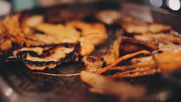 dichtbij omhoog schot van hand- Koken Koreaans gegrild varkensvlees buik vlees en gebruik schaar naar besnoeiing vlees Aan ijzer rooster pan.varkensvlees buik Aan een grill, samgyupsal, koken varkensvlees buik Aan een pan, koreaans varkensvlees barbecue video