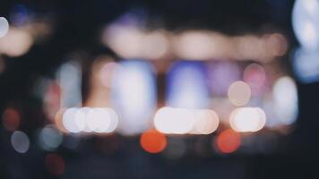 schön Bokeh im ein dunkel verschwommen Hintergrund beim Nacht auf das Gehen Straße mit das Personen. das runden bunt Bokeh scheinen von Gebäude und Geschäfte im das Stadt Lebensstil. abstrakt Konzept. video