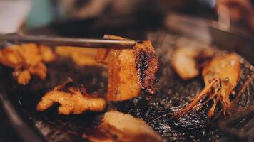 vicino su tiro di mano cucinando coreano grigliato Maiale pancia carne e uso forbici per tagliare carne su ferro griglia padella.maiale pancia su un' griglia, samgyupsal, cucina Maiale pancia su un' padella, coreano Maiale barbecue video