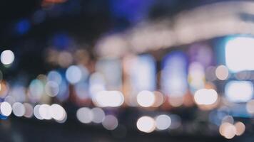 magnifique bokeh dans une foncé floue Contexte à nuit sur le en marchant rue avec le personnes. le rond coloré bokeh éclat de bâtiments et magasins dans le ville mode de vie. abstrait concept. video