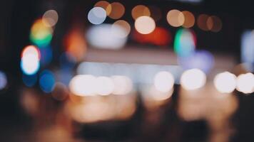 Beautiful bokeh in a dark blurry background at night on the walking street with the people. The round colorful bokeh shine from buildings and shops in the city lifestyle. Abstract concept. video