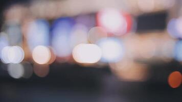 Beautiful bokeh in a dark blurry background at night on the walking street with the people. The round colorful bokeh shine from buildings and shops in the city lifestyle. Abstract concept. video