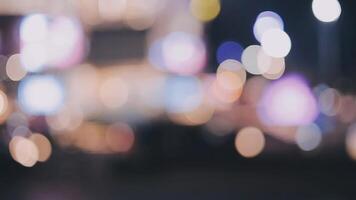 Beautiful bokeh in a dark blurry background at night on the walking street with the people. The round colorful bokeh shine from buildings and shops in the city lifestyle. Abstract concept. video