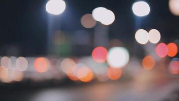 schön Bokeh im ein dunkel verschwommen Hintergrund beim Nacht auf das Gehen Straße mit das Personen. das runden bunt Bokeh scheinen von Gebäude und Geschäfte im das Stadt Lebensstil. abstrakt Konzept. video