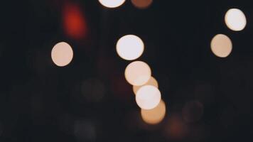 bellissimo bokeh nel un' buio sfocato sfondo a notte su il a piedi strada con il le persone. il il giro colorato bokeh brillare a partire dal edifici e negozi nel il città stile di vita. astratto concetto. video