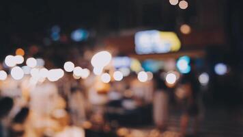 schön Bokeh im ein dunkel verschwommen Hintergrund beim Nacht auf das Gehen Straße mit das Personen. das runden bunt Bokeh scheinen von Gebäude und Geschäfte im das Stadt Lebensstil. abstrakt Konzept. video