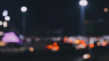 bellissimo bokeh nel un' buio sfocato sfondo a notte su il a piedi strada con il le persone. il il giro colorato bokeh brillare a partire dal edifici e negozi nel il città stile di vita. astratto concetto. video