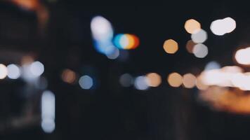 schön Bokeh im ein dunkel verschwommen Hintergrund beim Nacht auf das Gehen Straße mit das Personen. das runden bunt Bokeh scheinen von Gebäude und Geschäfte im das Stadt Lebensstil. abstrakt Konzept. video