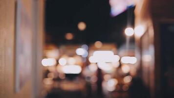 schön Bokeh im ein dunkel verschwommen Hintergrund beim Nacht auf das Gehen Straße mit das Personen. das runden bunt Bokeh scheinen von Gebäude und Geschäfte im das Stadt Lebensstil. abstrakt Konzept. video