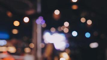 Beautiful bokeh in a dark blurry background at night on the walking street with the people. The round colorful bokeh shine from buildings and shops in the city lifestyle. Abstract concept. video